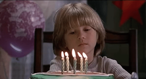 Gif of a sad boy sitting in front of his birthday cake.