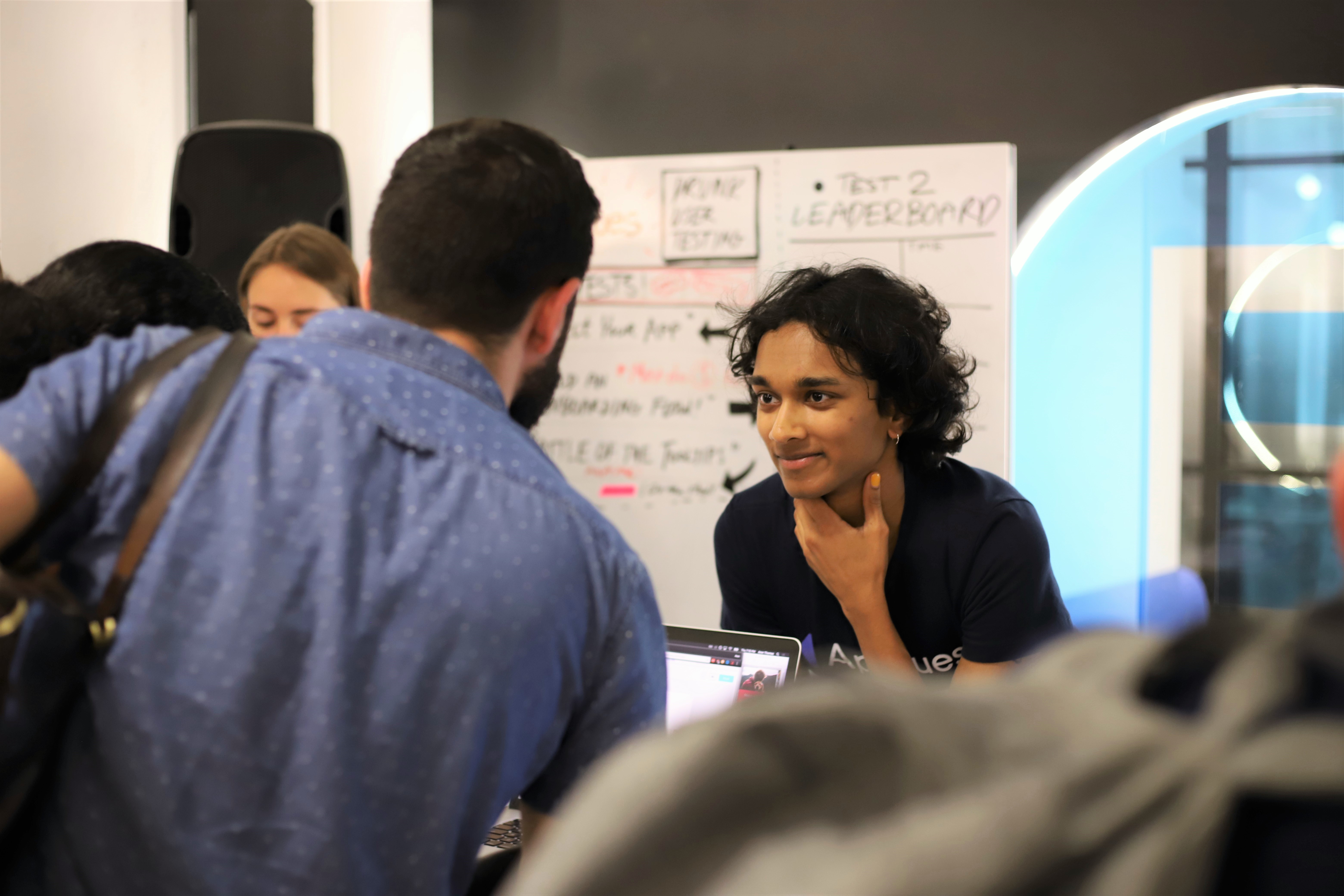 This is a photo of a product developer talking to a user in person at a user testing event, listening to user feedback about the product.