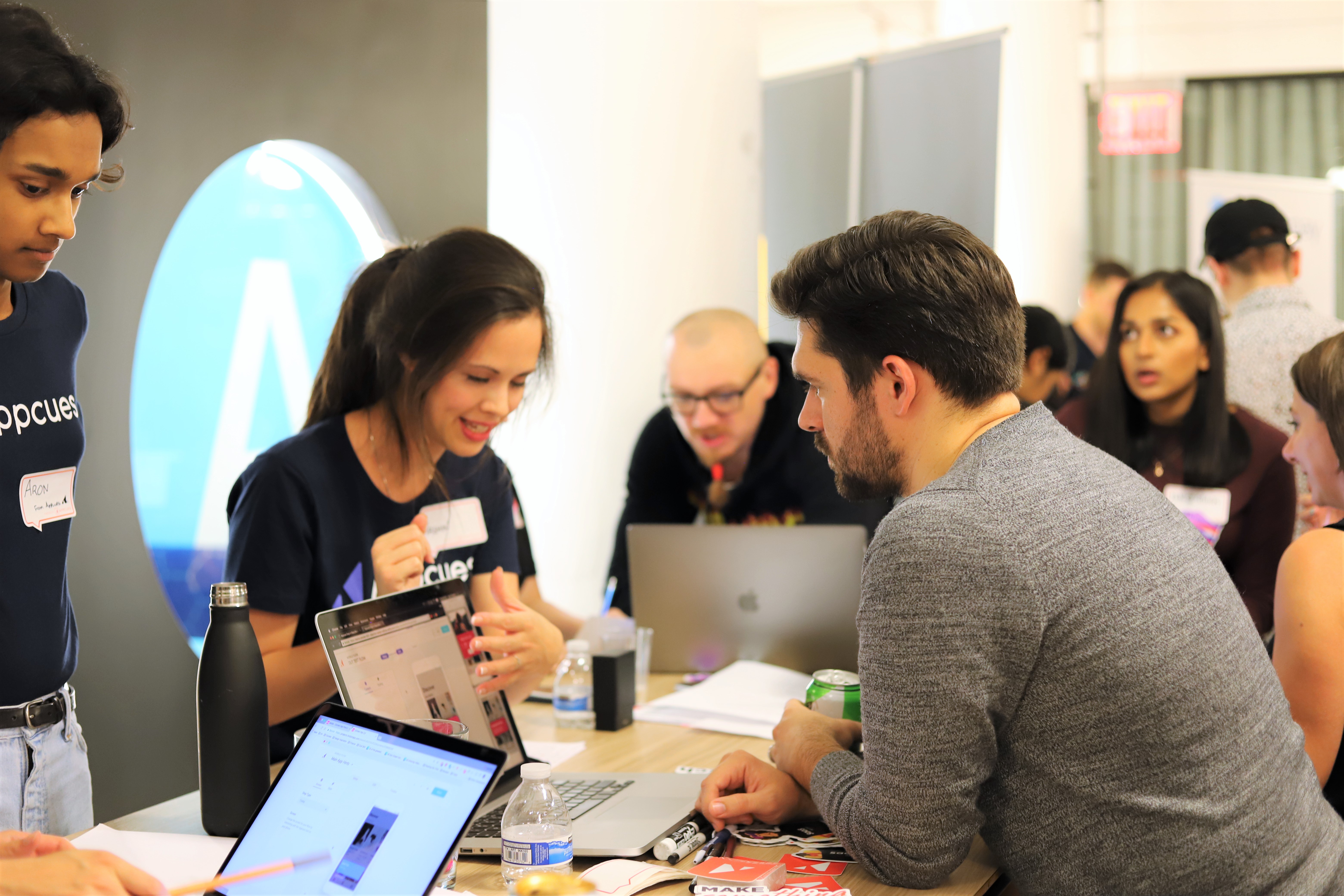 This is an image of people at a user testing event hosted by Appcues called User Test Fest. Two engineers and developers are talking to a user tester and explaining features on a laptop.